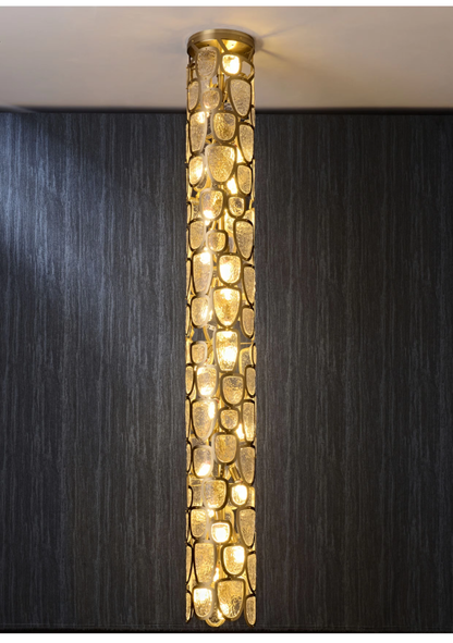 Lit crystal mosaic column LED pendant lamp with warm glow against dark wall